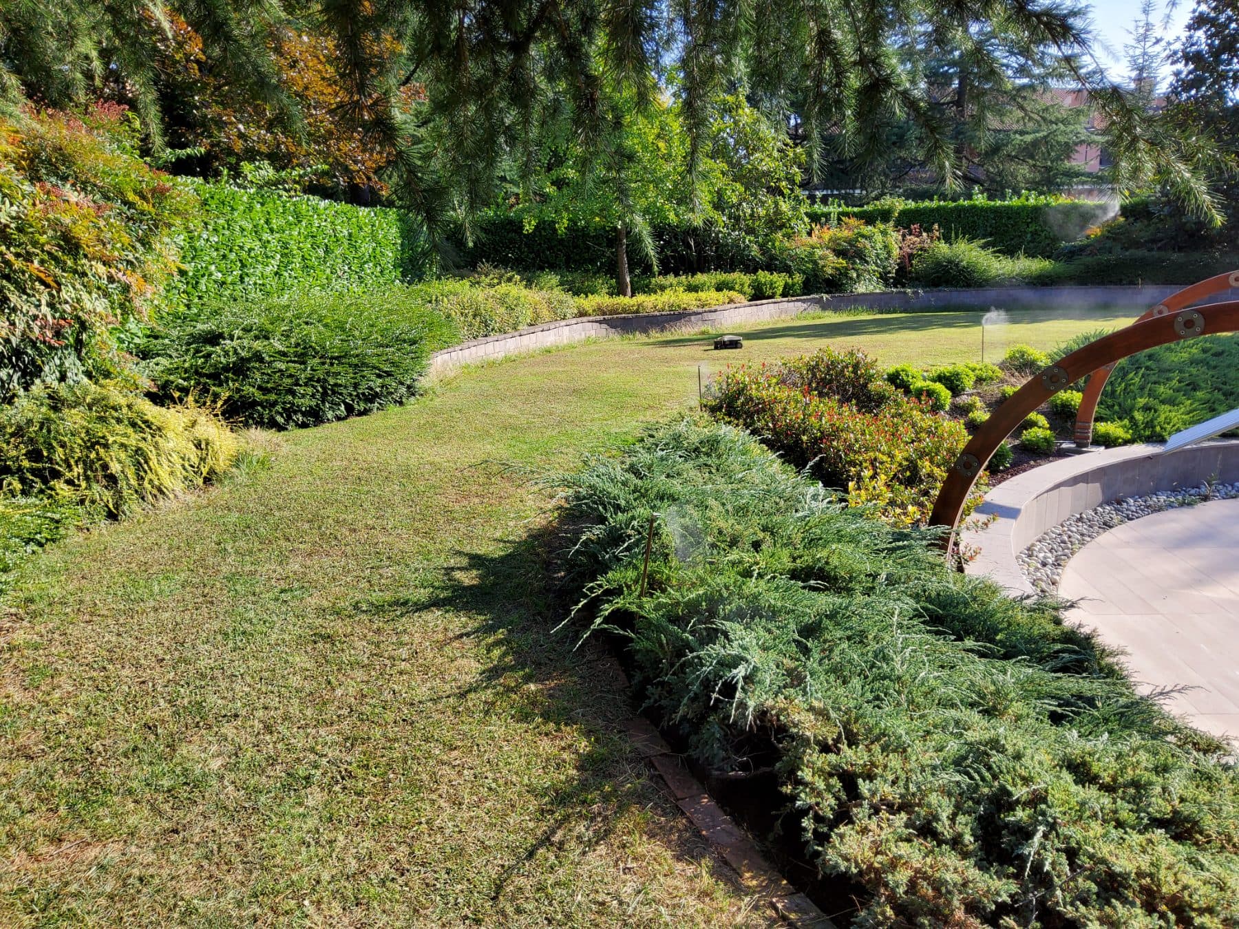 Prato curvo di un parco privato con bordure e nebulizzazione visibile sul fondo